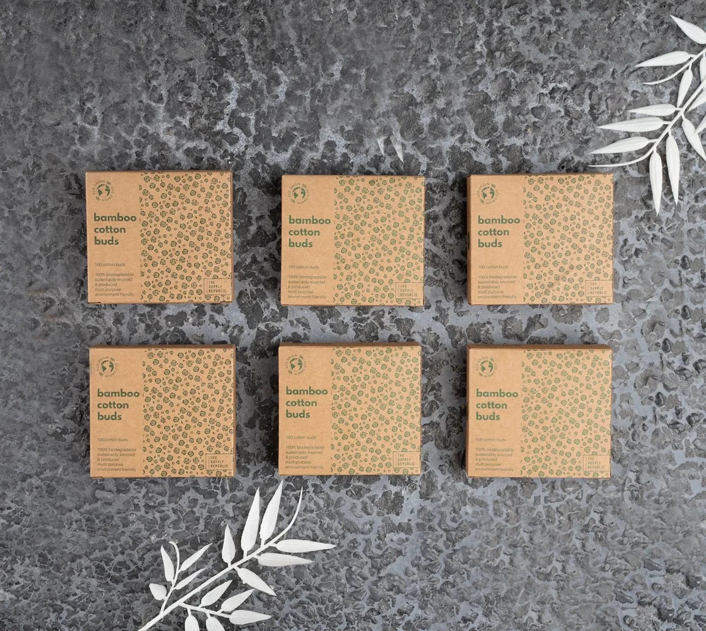Six cotton bud boxes in a grid on gray stone with leaves