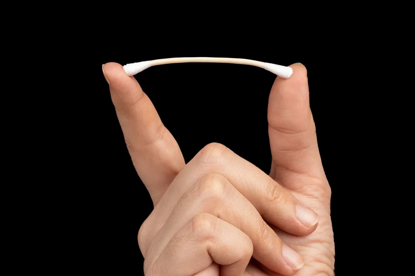 Fingers bending a bamboo cotton bud to show flexibility