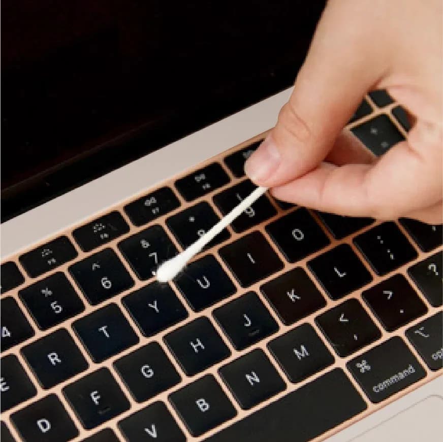 Cotton bud cleaning a laptop keyboard
