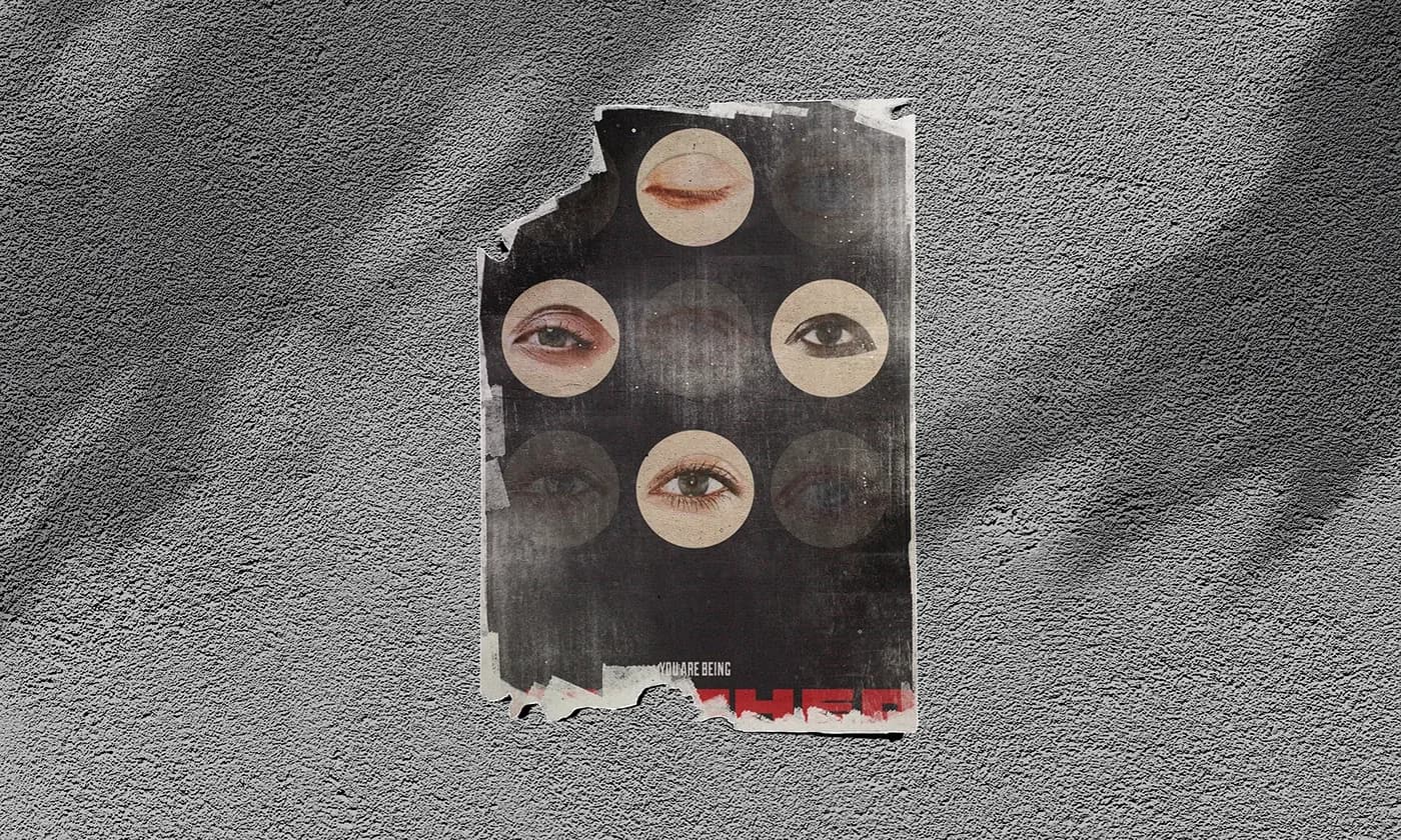 Torn, weathered poster of collaged eyes pasted on a rough gray wall