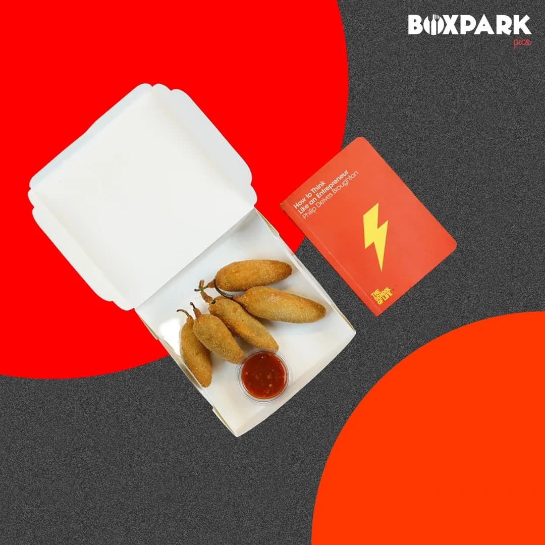 Jalapeno poppers in an open white box beside a red book