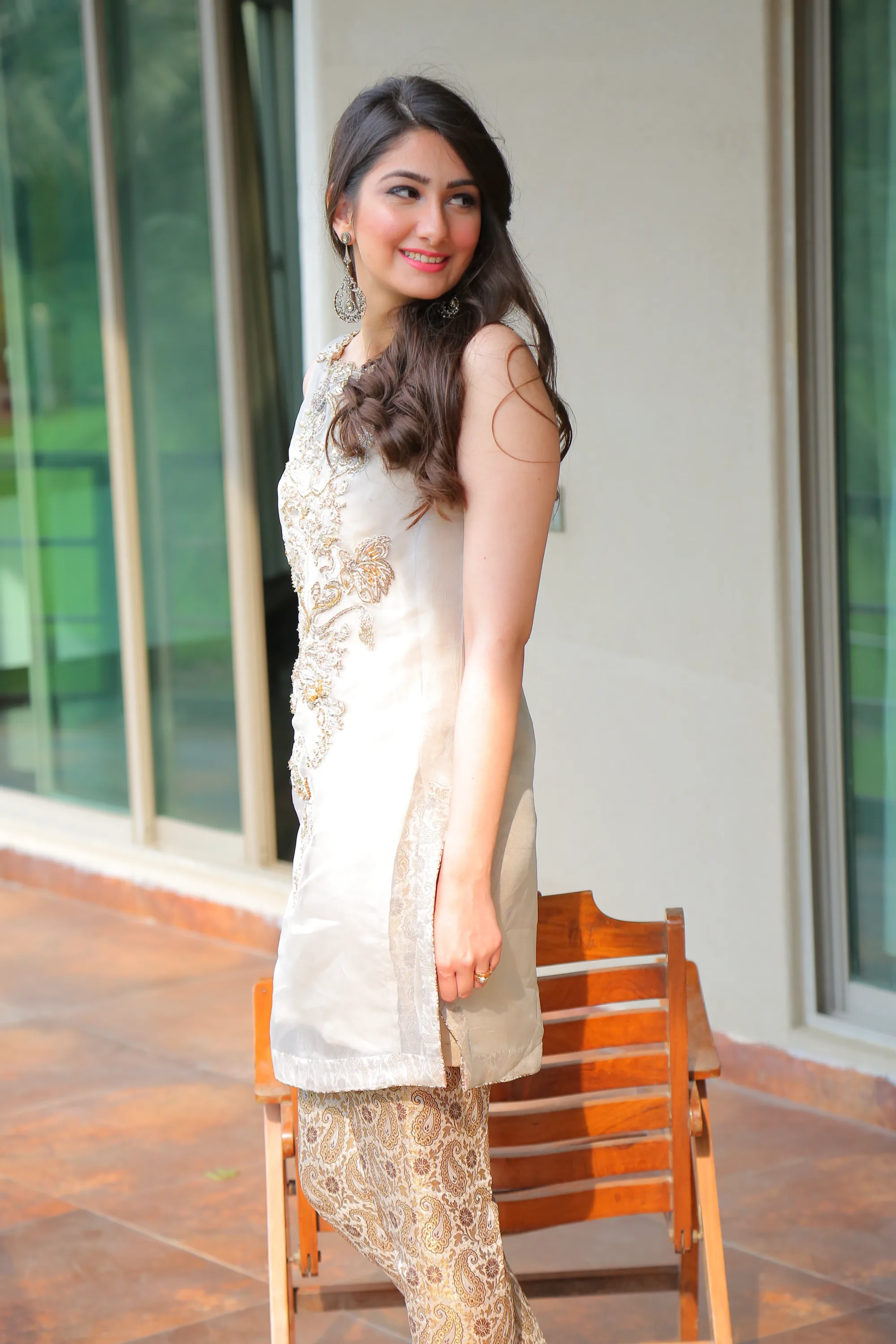 Model in an embroidered beige kurta and paisley trousers on a sunlit terrace