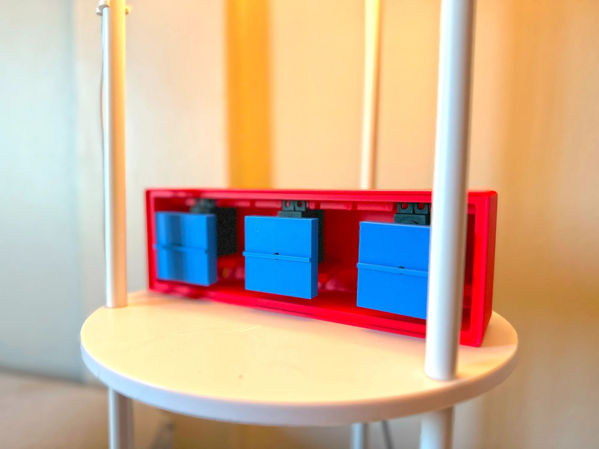 Red homing beacon with three blue cubes on a white side table