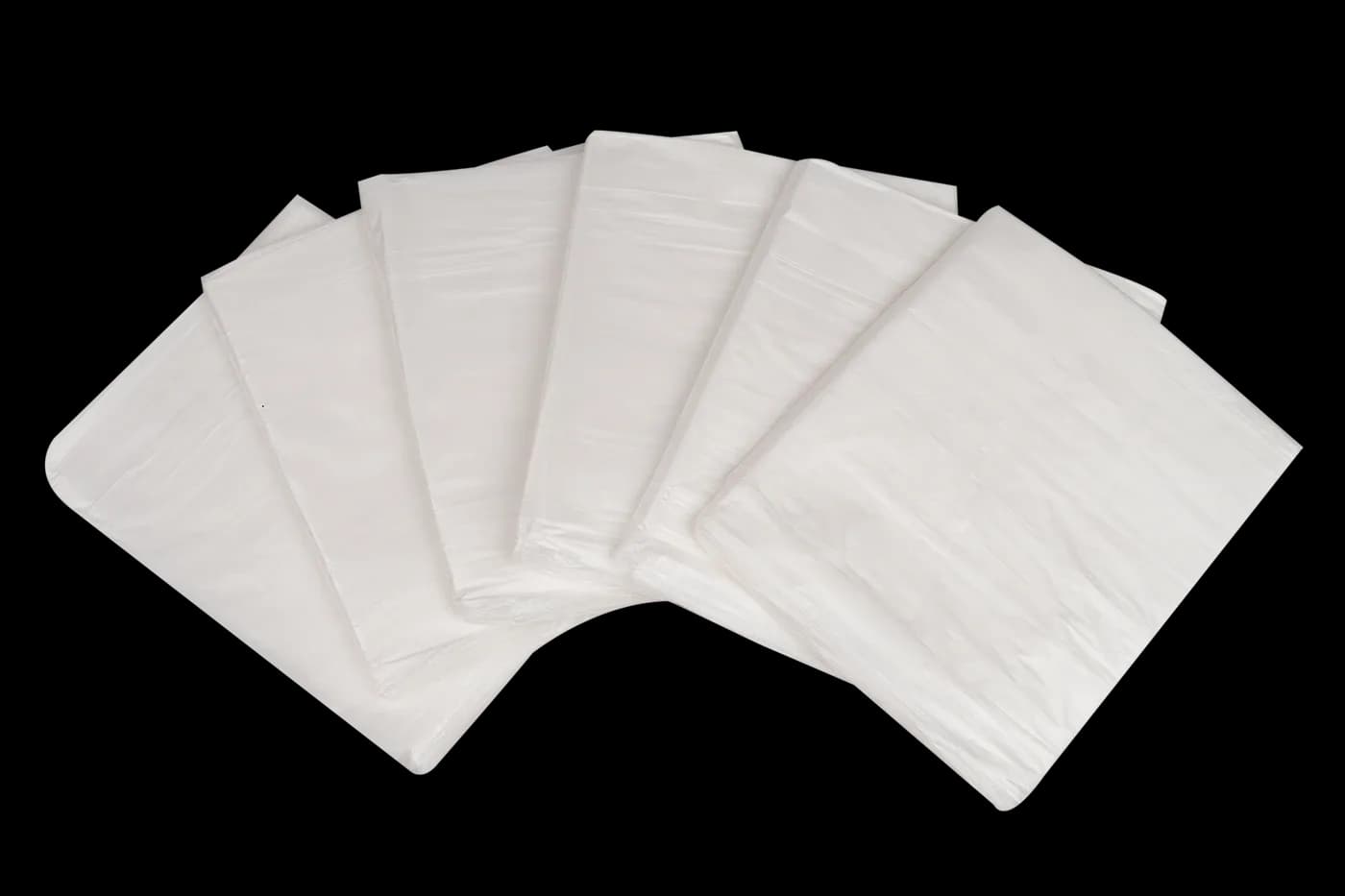 Six folded white dust sheets fanned out on black
