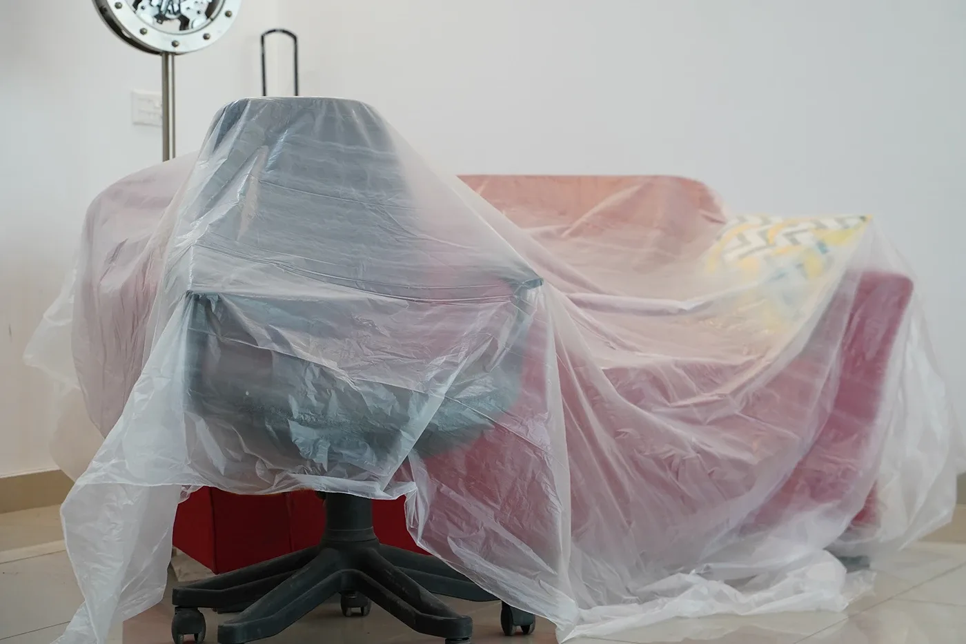 Office chair and sofa covered with a clear dust sheet