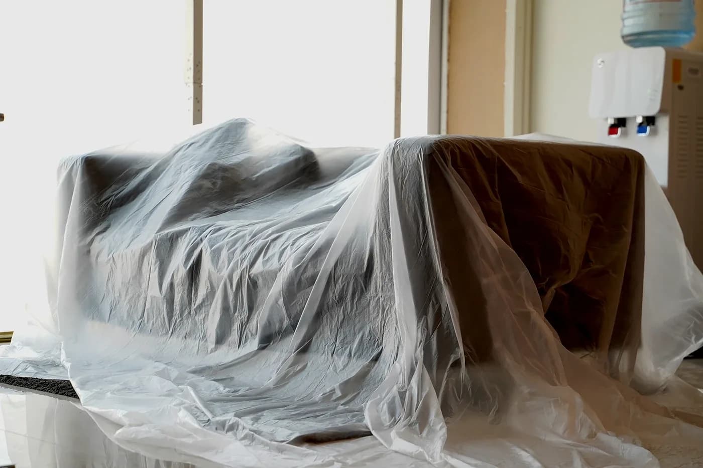 Sofa draped in a clear plastic dust sheet