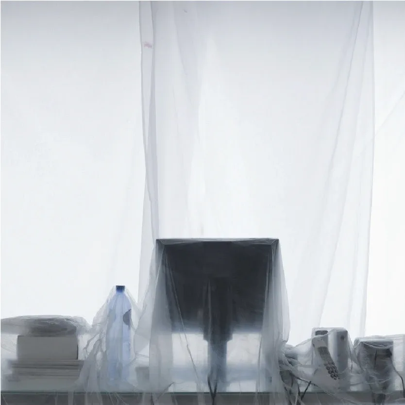 Monitor and desk items under a clear dust sheet