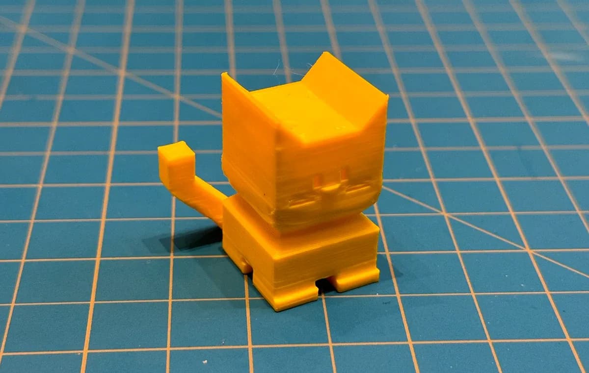 3D printed orange cat figure on a cutting mat