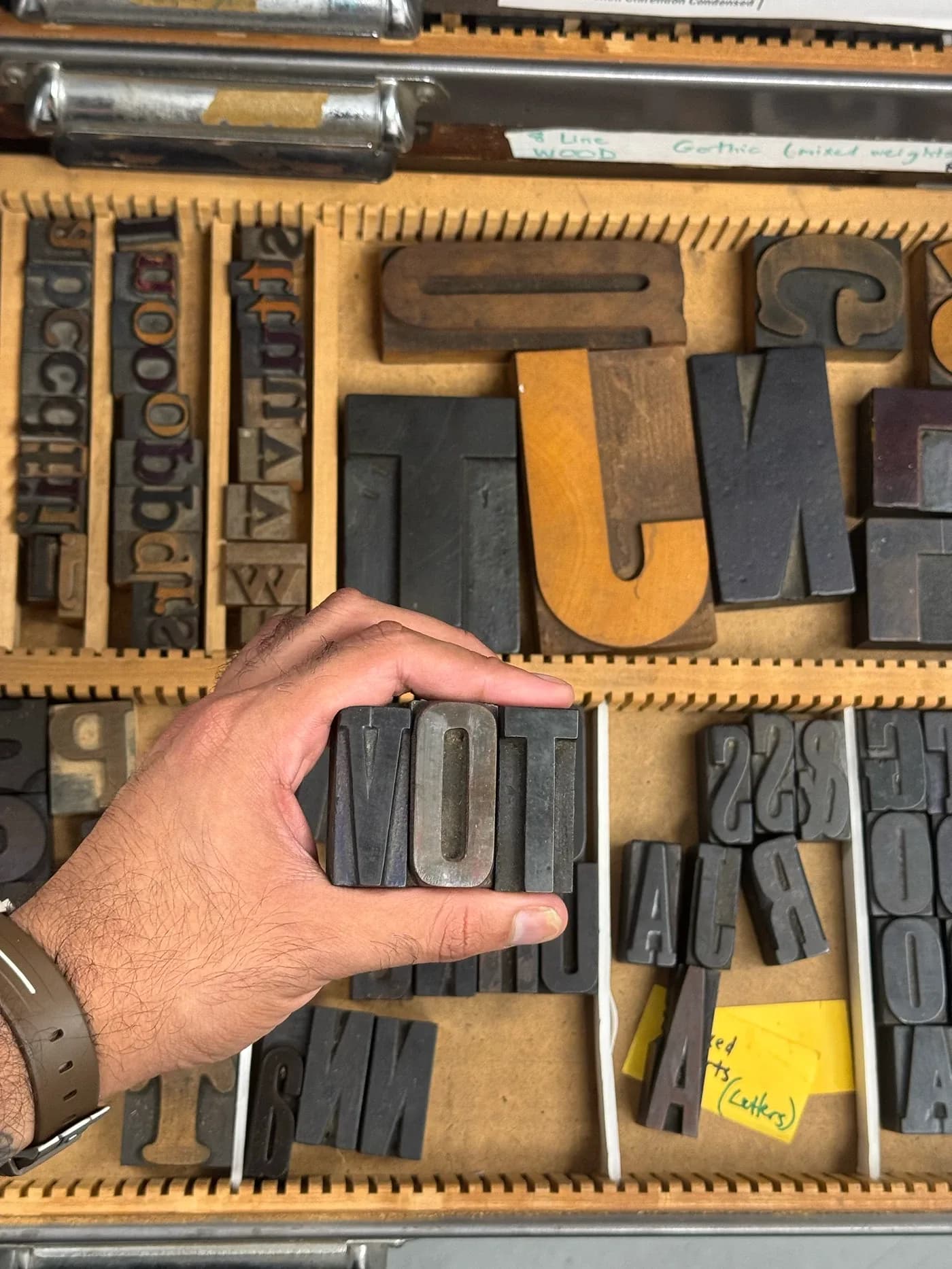 Hand selecting wood type letters from a tray