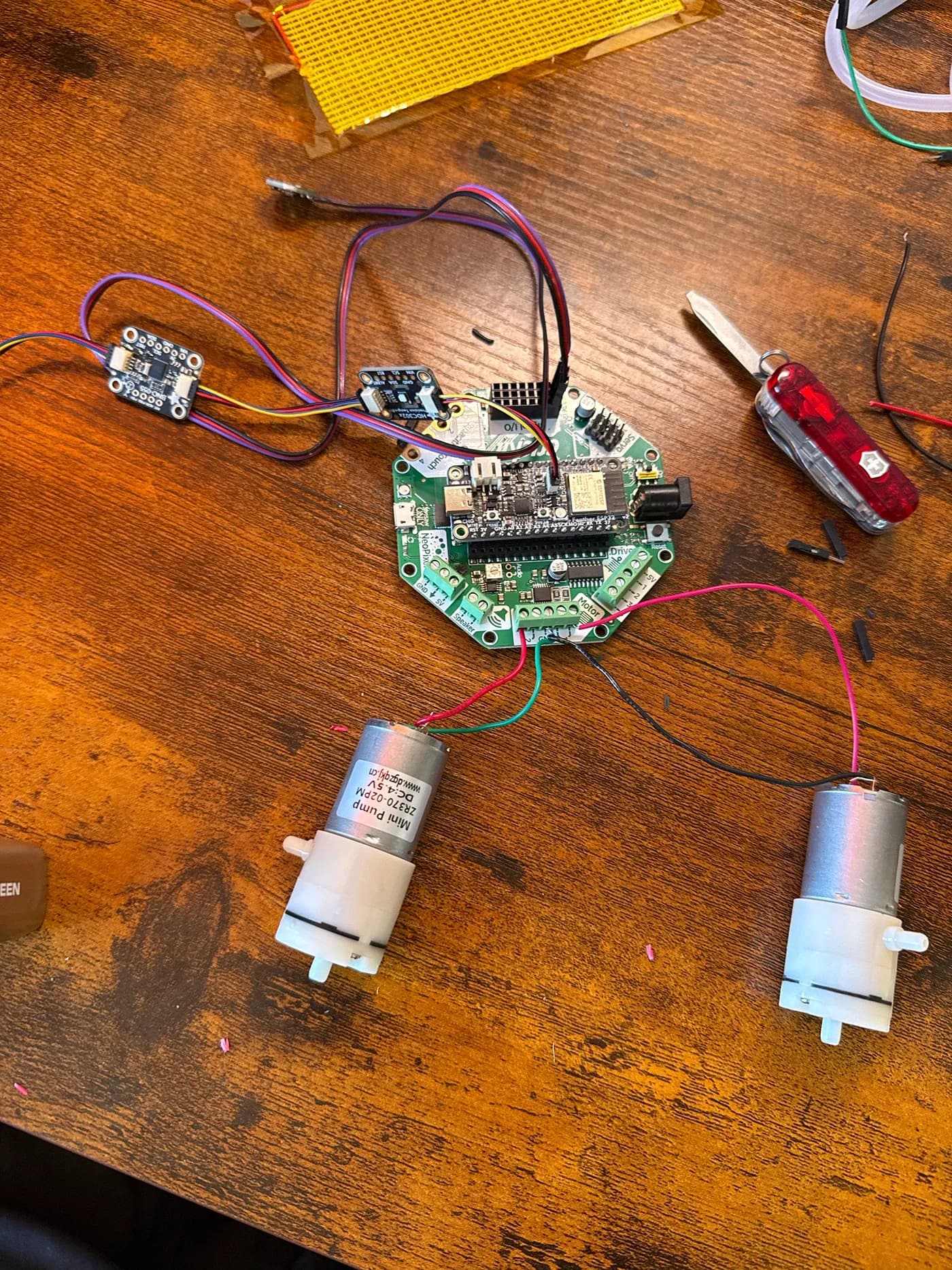 Board wired to two small air pumps on a wooden desk
