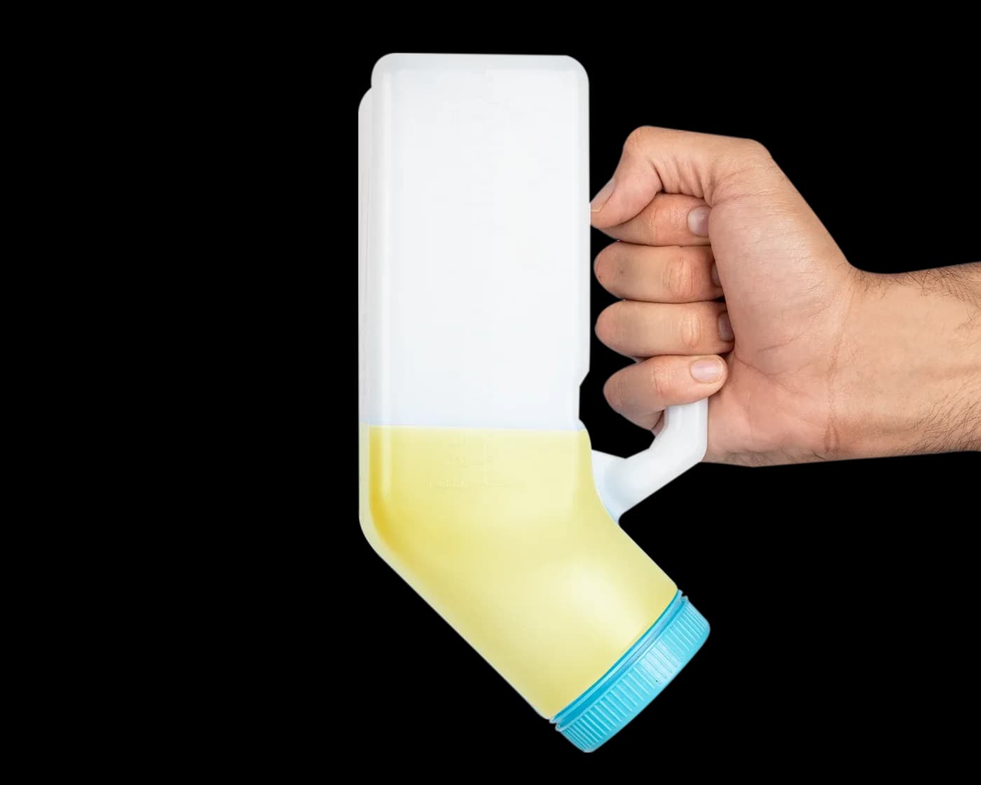 Hand holding the bottle tilted, partly filled with yellow liquid
