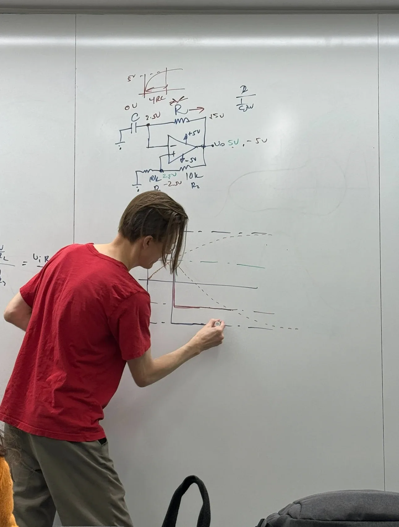 Student sketching a circuit diagram on a whiteboard