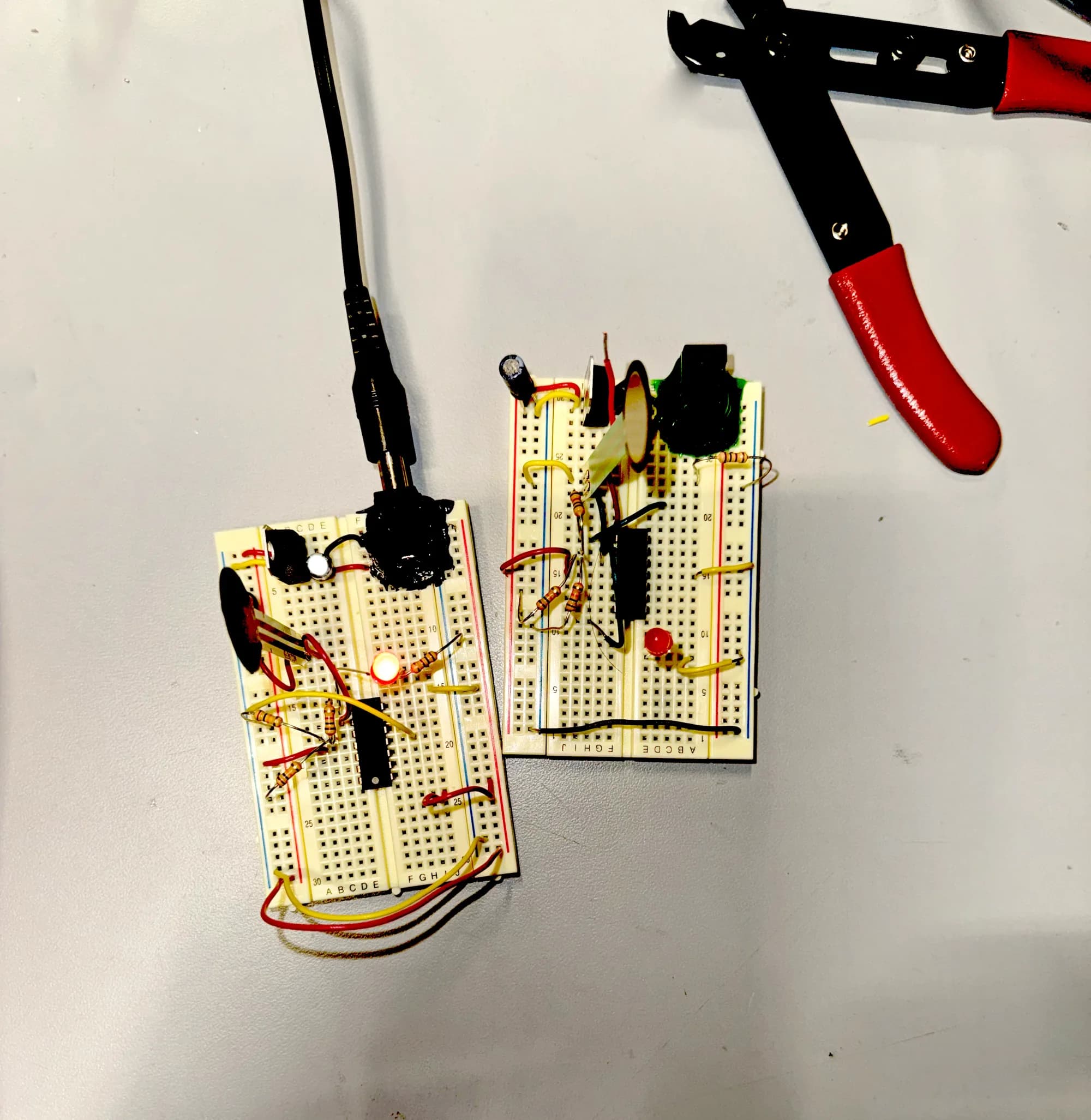 Two breadboard circuits with audio jacks beside wire cutters