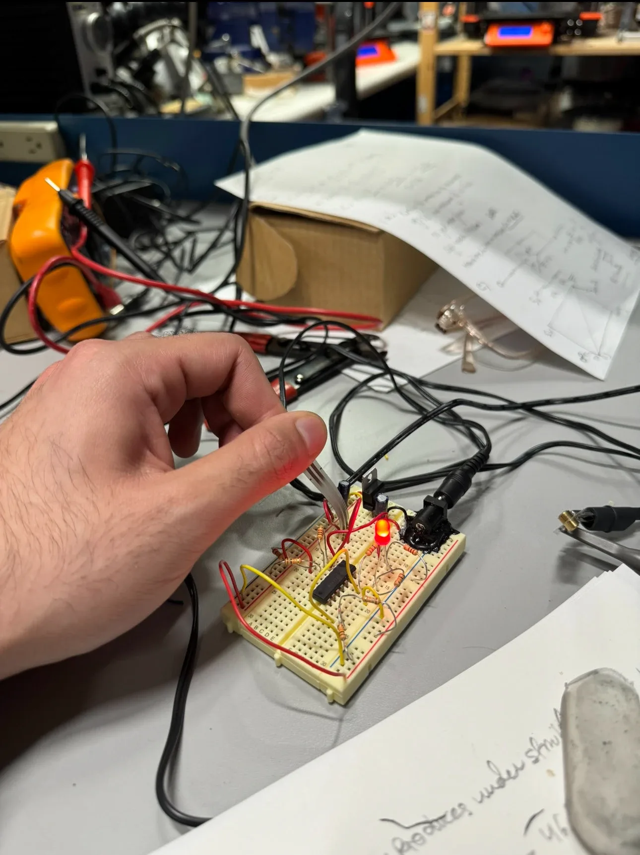 Hand testing a breadboard circuit with multimeter leads