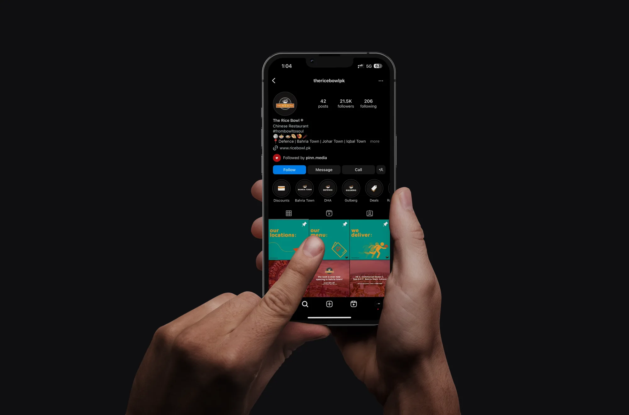 Hand holding phone showing The Rice Bowl Instagram profile with teal pinned posts
