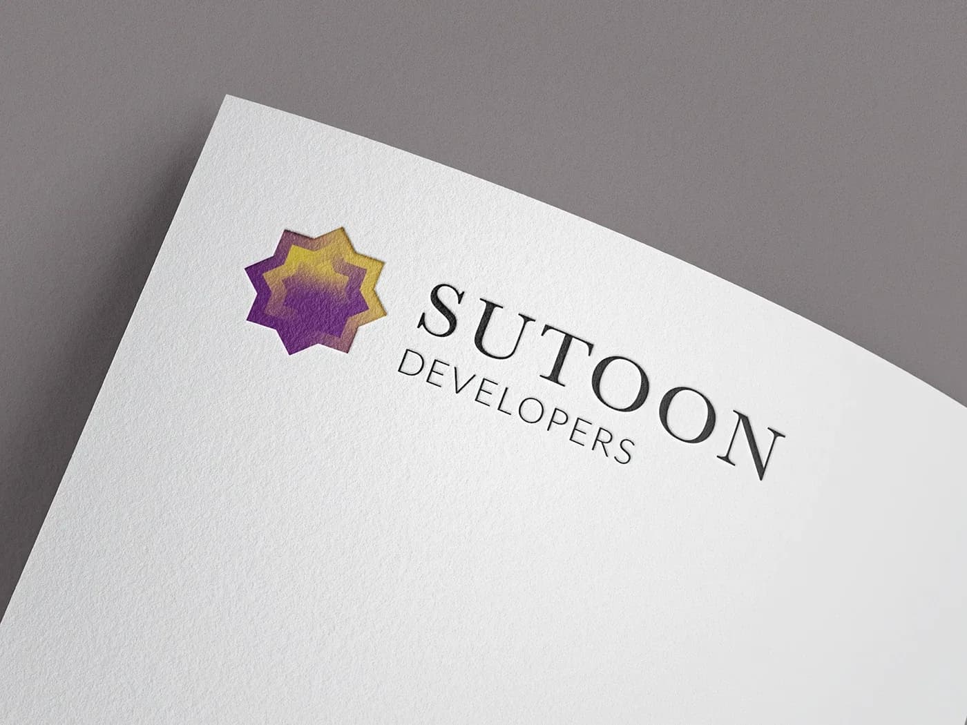 Sutoon Developers logo with purple and gold star debossed on white paper