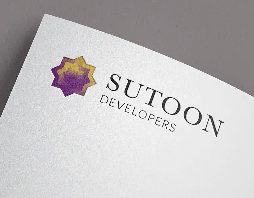 Sutoon Developers logo, a purple and gold eight-point star beside a serif wordmark, debossed on white textured paper