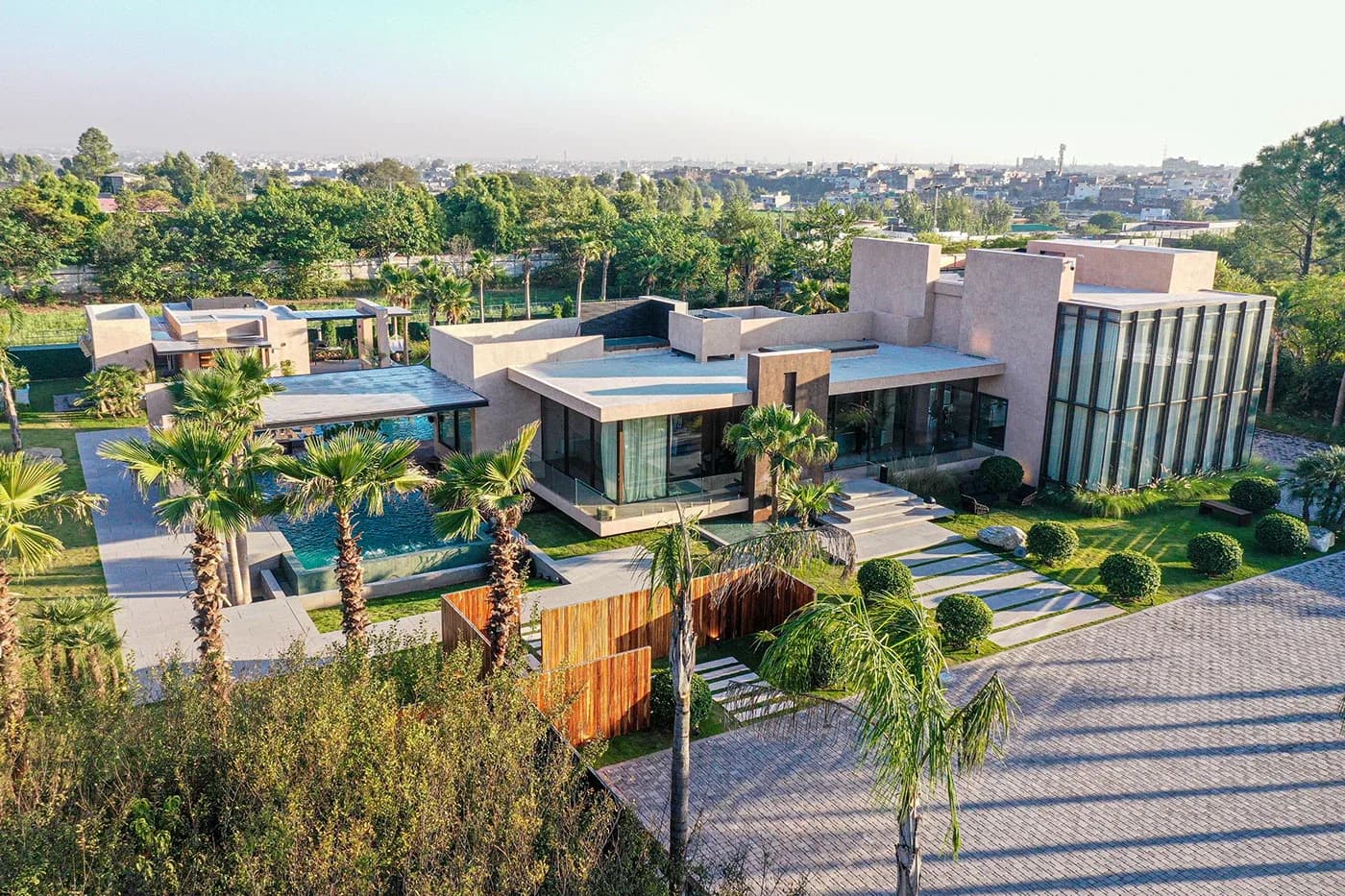 Aerial view of the house, pool and paved forecourt at golden hour