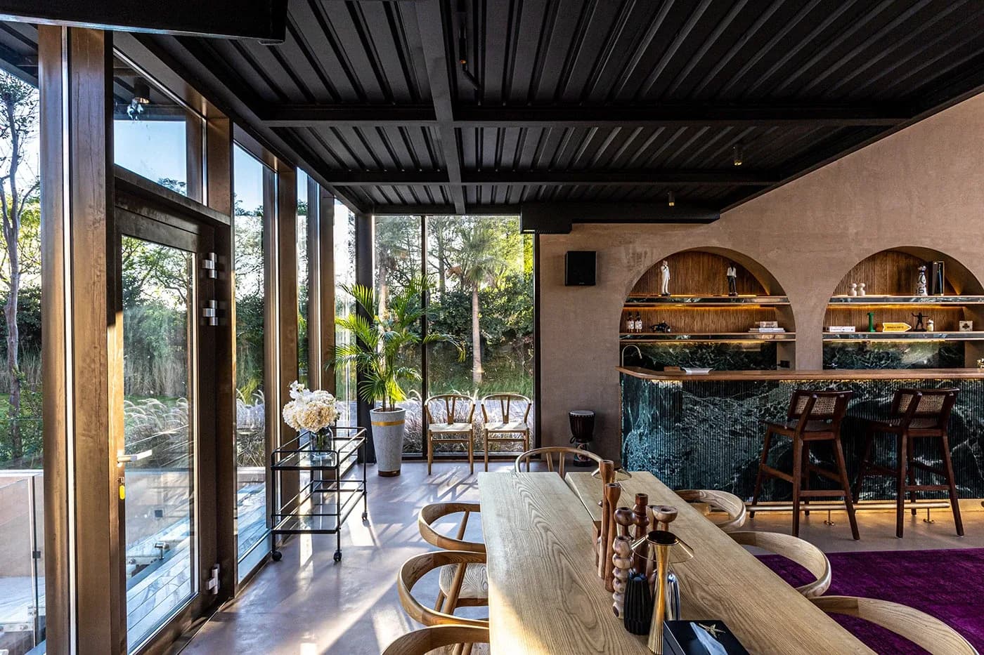 Dining area with long wooden table and arched bar shelves
