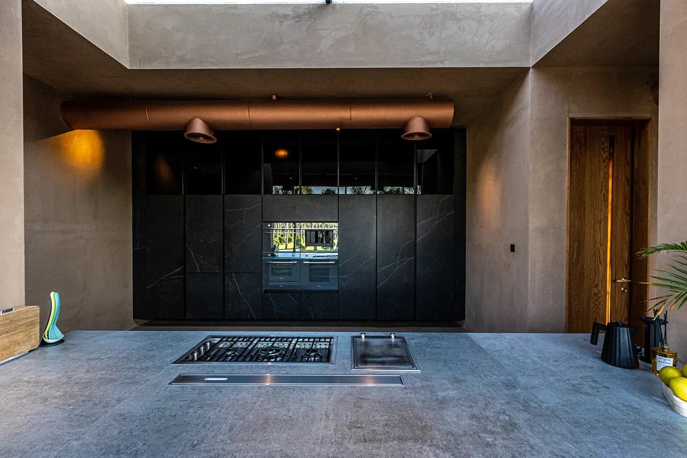 Kitchen with black marble cabinetry and concrete island
