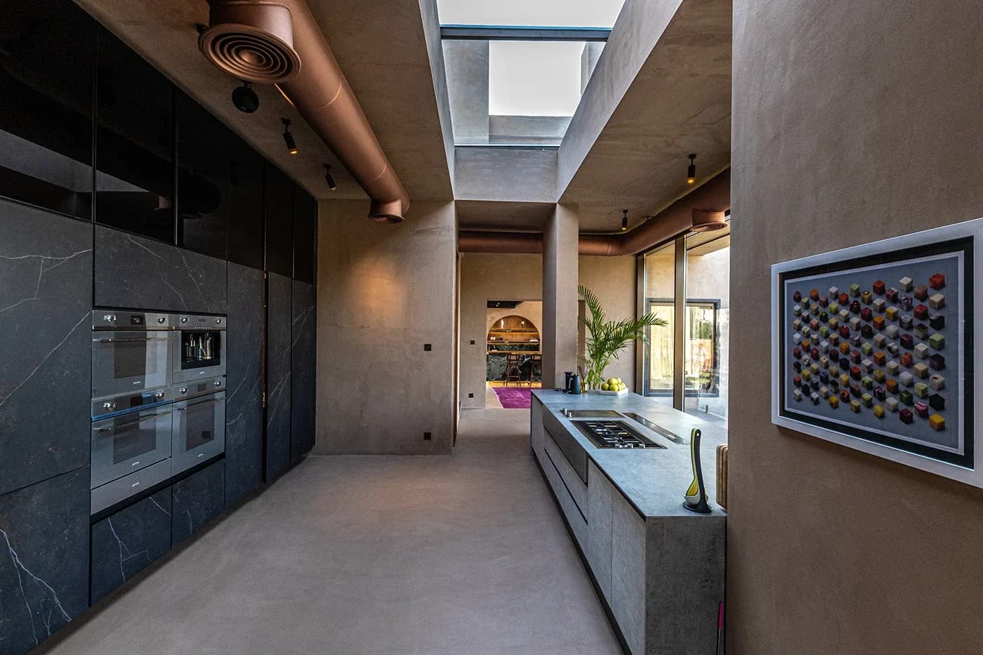 Galley kitchen with black ovens and framed wall art