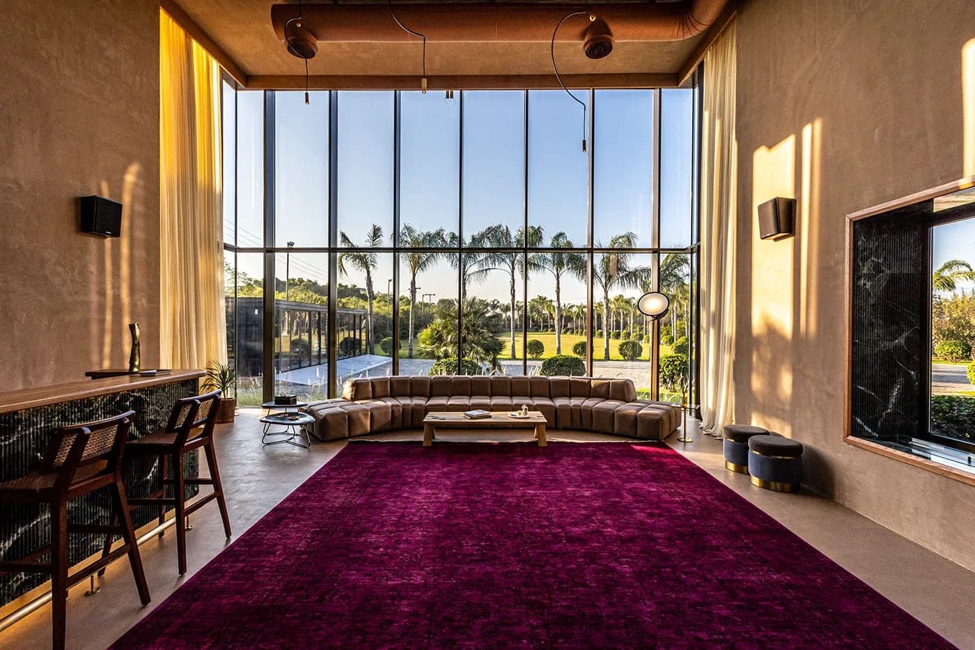 Double-height living room with magenta rug and glass wall