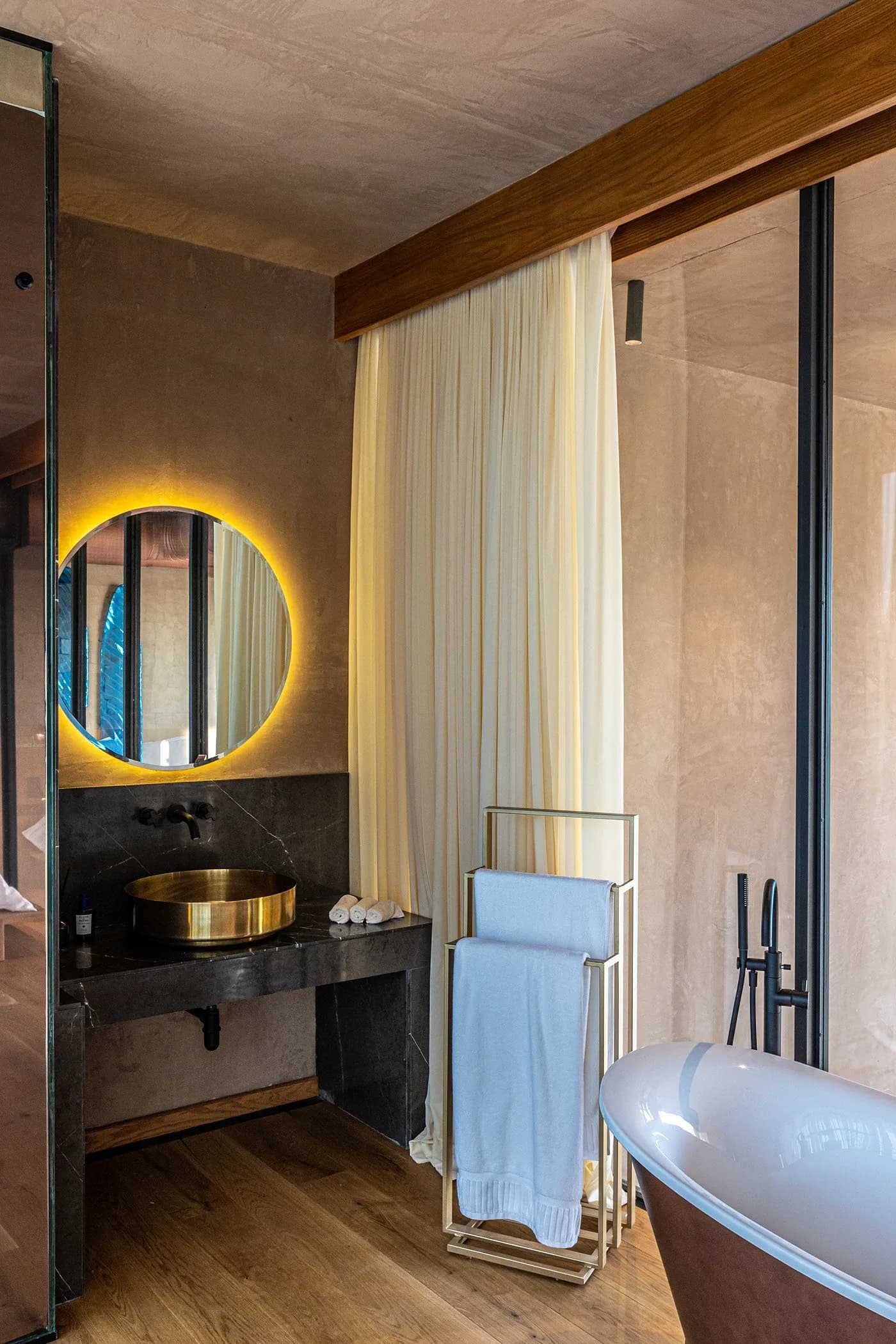 Bathroom with backlit round mirror and brass basin