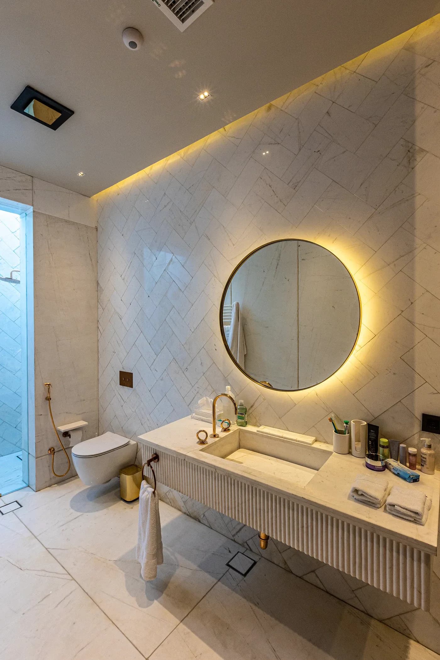 White herringbone-tiled bathroom with backlit mirror