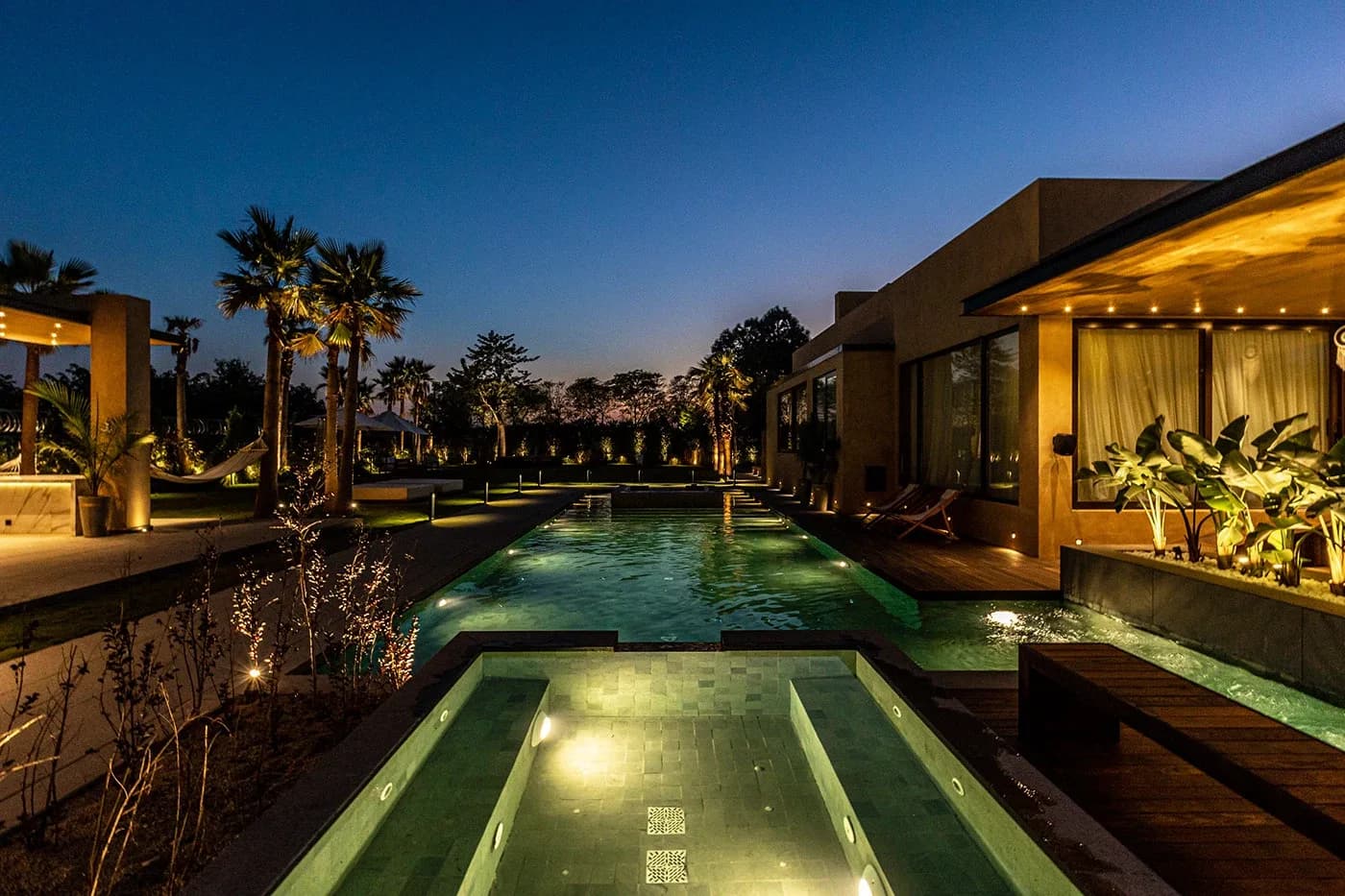 Pools and terraces lit at night among palms