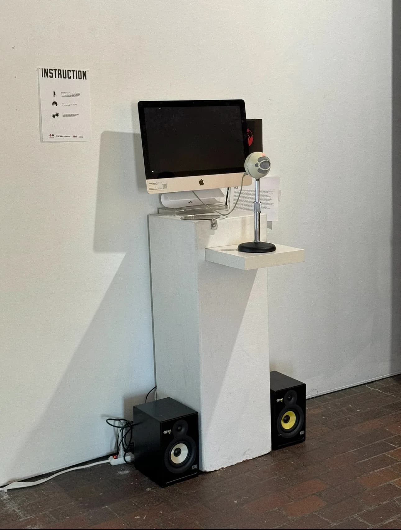 Uncense installation: monitor, microphone and speakers on a white plinth
